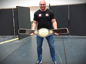 Na zdjęciu mężczyzna trzymający w rękach zdobyty złoty pas.