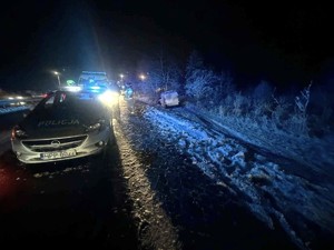 Na zdjęciu w porze nocnej widzimy na jezdni radiowóz policyjny i samochody innych służb oraz w rowie samochód dostawczy.