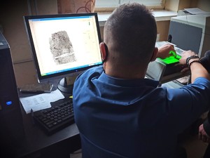 Na zdjęciu Technik kryminalistyki pobiera odciski palców.