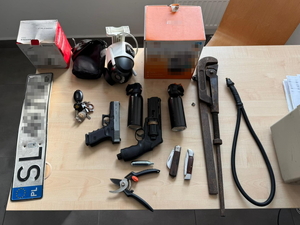 Na zdjęciu zabezpieczone przez policjantów przedmioty. W tym broń, tablica rejestracyjna, noże, kamery.