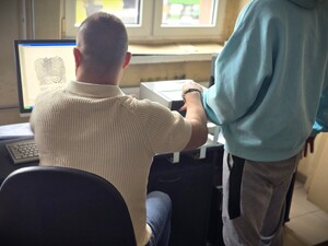 Na zdjęciu technik kryminalistyki pobiera odciski palców zatrzymanemu.