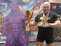 Na zdjęciu mężczyzna trzymający puchar i medale.