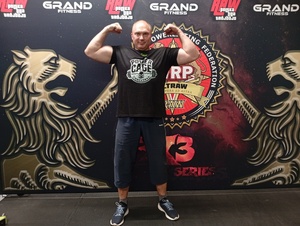 Na zdjęciu mężczyzna w stroju sportowym z uniesionymi ramionami.