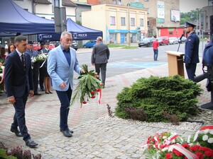Przedstawiciele władz samorządowych składają kwiaty pod pomnikiem, przed budynkiem komendy.