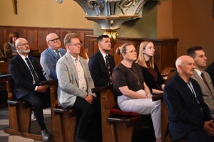 Zdjęcie grupowe gości w kościele, którzy siedzą w ławkach.