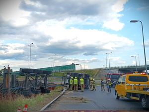 Na zdjęciu widzimy przewróconą ciężarówkę na łuku drogi oraz służby w akcji.