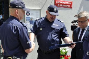 na zdjęciu wojewoda śląski oraz szef śląskich policjantów przekazujący symboliczny klucz kierownikowi posterunku