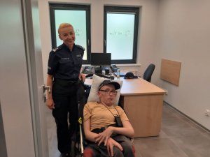 Policjantka i chłopak na wózku inwalidzkim zwiedzają posterunek policji.