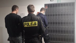 Policjanci doprowadzają zatrzymanego do policyjnego aresztu.