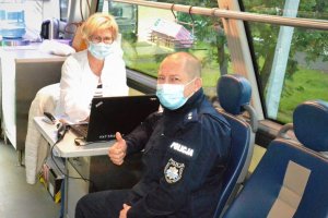 Policjant wykonuje kciukiem znak OK podczas wywiadu lekarskiego przed oddaniem krwi