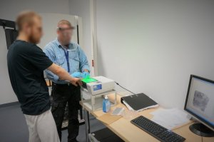 Policyjny technik popiera od podejrzanego odciski palców