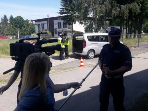 Naczelnik Wydziału Ruchu Drogowego w Bielsku-Białej udziela wywiadu telewizji. W tle policjanci operują dronem.