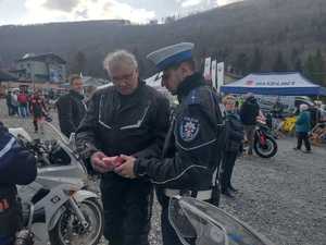 Policjant przekazuje motocykliście apteczkę pierwszej pomocy