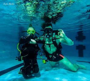Fotografia wykonana pod wodą - podkomisarz Dariusz Stypułkowski wraz z synem w strojach i z osprzętem do nurkowania