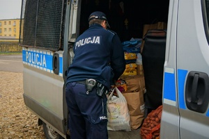 Na zdjęciu policjant wkłada do radiowozu torbę z darami