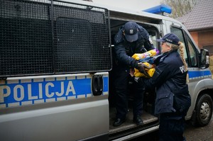 Na zdjęciu policjanci wyjmują z radiowozu duże opakowania z karmą dla zwierząt