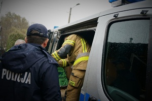 Na zdjęciu policjant i strażak wyciągają z radiowozu zebrane dary