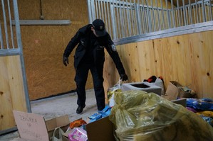 Na zdjęciu policjant w stajni układa zebrane dary