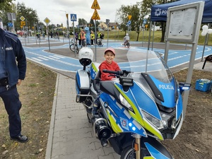 Na zdjęciu widzimy policjanta oraz motocykl służbowy, na którym siedzi dziecko