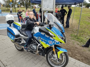 Na zdjęciu widzimy policjanta oraz motocykl służbowy, na którym siedzi dziecko