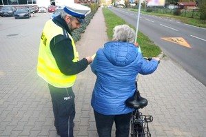 Na zdjęciu widzimy policjanta jak daje odblask