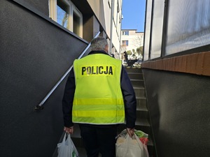 Na zdjęciu widzimy policjanta w czasie przekazywania darów dla przytuliska