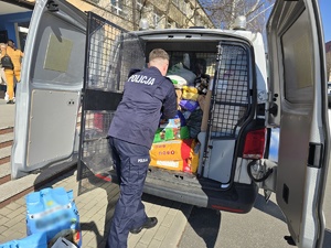 Na zdjęciu widzimy policjanta w czasie przekazywania darów dla przytuliska