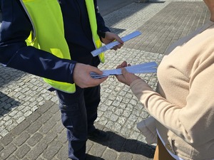 Na zdjęciu widzimy policjanta dającego odblask