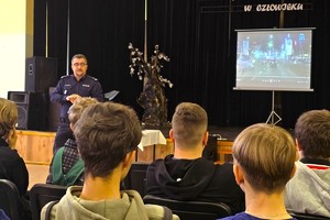 Na zdjęciu widzimy czapkę policyjną oraz uczniów w czasie profilaktyki