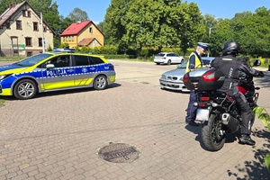 Na zdjęciu widzimy policjanta oraz motocyklistę w trakcie kontroli drogowej