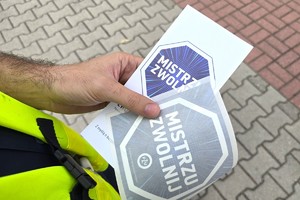 Na zdjęciu widzimy policjanta oraz kierującego z ulotkami oraz naklejką Mistrzu Zwolnij
