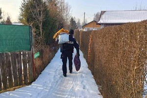 Na zdjęciu widzimy policjanta przekazującego najpotrzebniejsze rzeczy osobą w kryzysie bezdomności