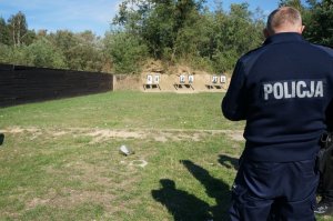 Policjant stoi przed tarczą strzelniczą