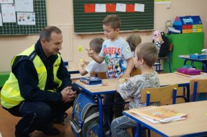 Policjant kucający prze ławce rozmawia z uczniem