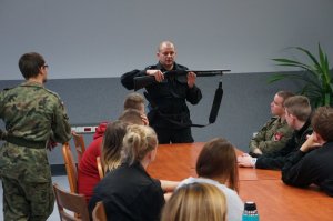 Policjant pokazuje uczniom broń gładkolufową