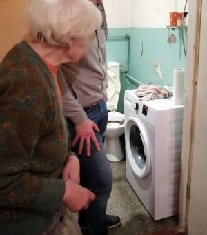 Policjant ustawia pralkę w łazience seniorki