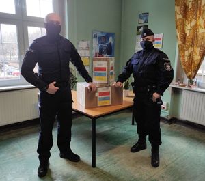 Policjanci w mundurach z paczkami w pomieszczeniu komisariatu