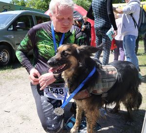 Uczestnik zawodów ze swoim psem z medalami