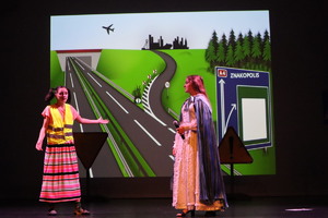 Na scenie dwie występujące dziewczyny, w tle widoczna droga.