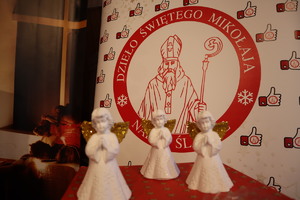 Zdjęcie przedstawia trzy gipsowe aniołki i plakat przedstawiający Świętego Mikołaja.