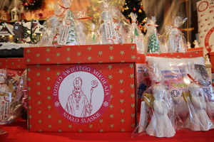 Prezenty i pudełko z wizerunkiem Świętego Mikołaja z napisem Dzieło Świętego Mikołaja.