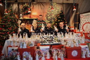 Zdjęcie przedstawia policjantów wśród prezentów i ustrojonych świątecznie choinek.