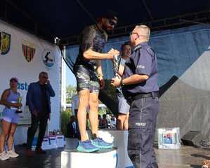 Zdjęcie przedstawia zawodnika na podium, któremu puchar wręcza Komendant Miejski Policji w Bytomiu.