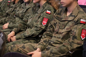 Na zdjęciu kilka siedzących sylwetek osób ubranych w mundurowe stroje moro.