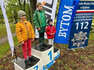 Na zdjęciu trójka dzieci stojących na podium z medalami zawieszonymi na szyjach.