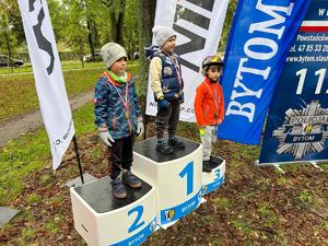 Na zdjęciu trójka dzieci stojących na podium z medalami zawieszonymi na szyjach.