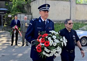 na zdjęciu Pierwszy Zastępca Komendanta Miejskiego Policji w Bytomiu młodszy inspektor Michał Sokołowski wraz z kapelanem księdzem Joachimem Gondro trzymający kwiaty., za nimi ojciec poległego policjanta oraz Prezydenta Miasta Bytomia Mariusz Wołosz