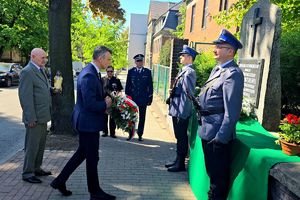 na zdjęciu Prezydent Miasta Bytomia wraz z ojcem poległego policjanta składający kwiaty przed pomnikiem przy którym stają dwaj policjanci, obok nich Pierwszy Zastępca Komendanta Miejskiego Policji w Bytomiu wraz z kapelanem.