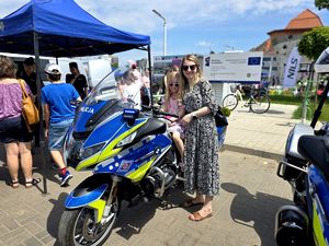 na zdjęciu siedząca na motocyklu policyjnym dziewczynka, obok niej kobieta
