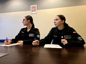 na zdjęciu dwie uczennice klasy mundurowej siedzące przy stole i piszące test